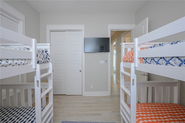 bedroom with a closet, light wood-style flooring, and baseboards