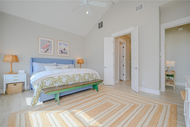 bedroom with light wood finished floors, baseboards, visible vents, and high vaulted ceiling