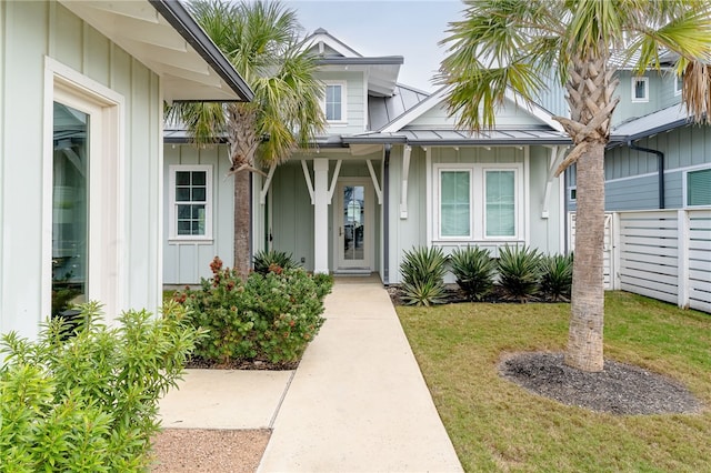 entrance to property with a standing seam roof, metal roof, a yard, and board and batten siding