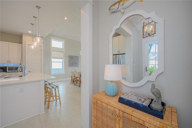 interior space featuring light tile patterned floors, baseboards, a sink, a notable chandelier, and recessed lighting