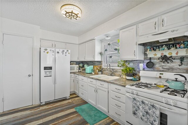 kitchen with dark wood-type flooring, light countertops, white cabinets, white appliances, and a sink