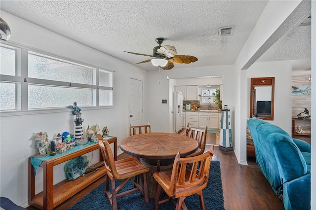 dining space featuring visible vents, dark wood-type flooring, ceiling fan, and a textured ceiling