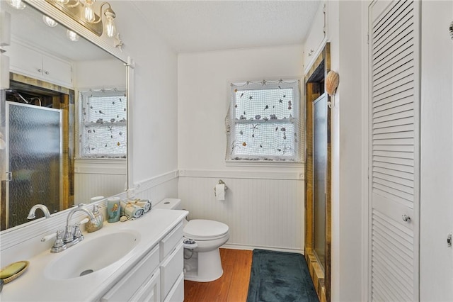 bathroom with wood finished floors, a healthy amount of sunlight, a closet, and wainscoting