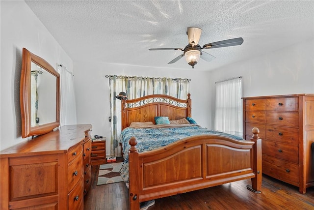 bedroom with ceiling fan, dark wood-style flooring, and a textured ceiling