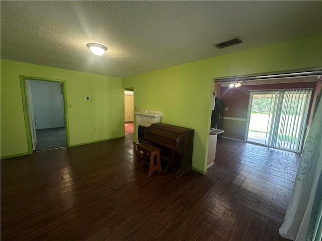 225 W Gile Ave, Aransas Pass, TX 78336 - empty room with a textured ceiling, visible vents, dark wood-style floors, and baseboards