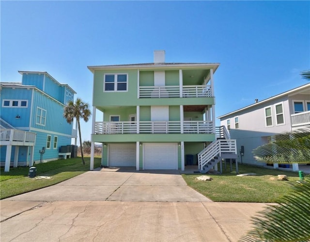 beach home with concrete driveway, an attached garage, a front yard, central AC, and stairs