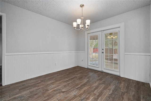 spare room featuring a chandelier, french doors, a textured ceiling, and dark wood-type flooring