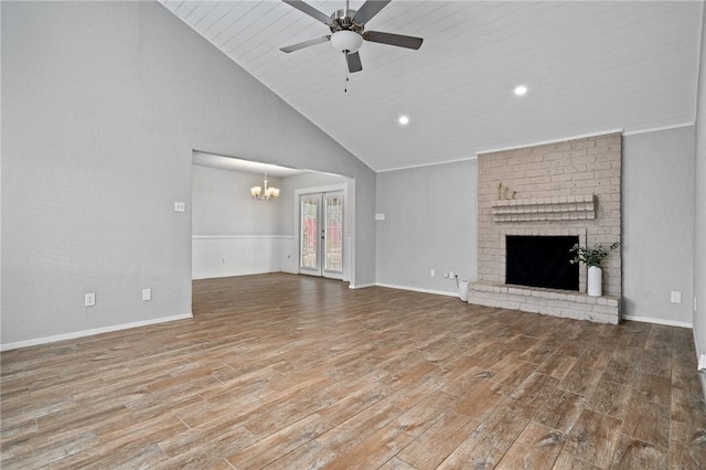 unfurnished living room with ceiling fan with notable chandelier, lofted ceiling, french doors, and a brick fireplace