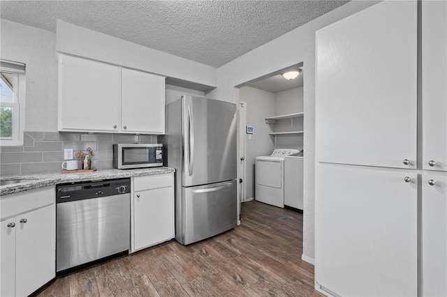 kitchen with backsplash, independent washer and dryer, white cabinetry, and stainless steel appliances