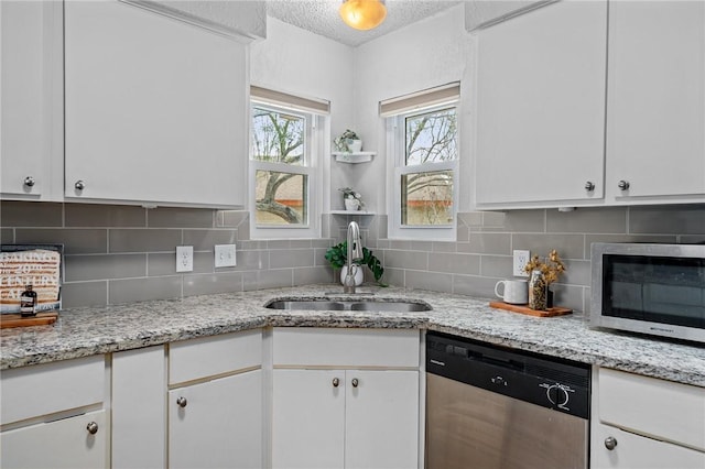 kitchen with sink, light stone counters, decorative backsplash, white cabinets, and appliances with stainless steel finishes