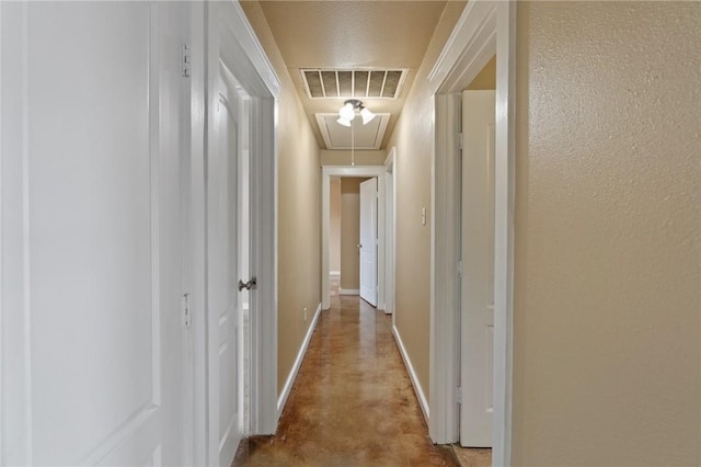 corridor with attic access, baseboards, visible vents, and finished concrete flooring