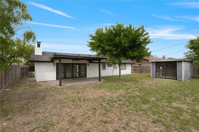 rear view of house with a yard, a chimney, a patio area, and a fenced backyard