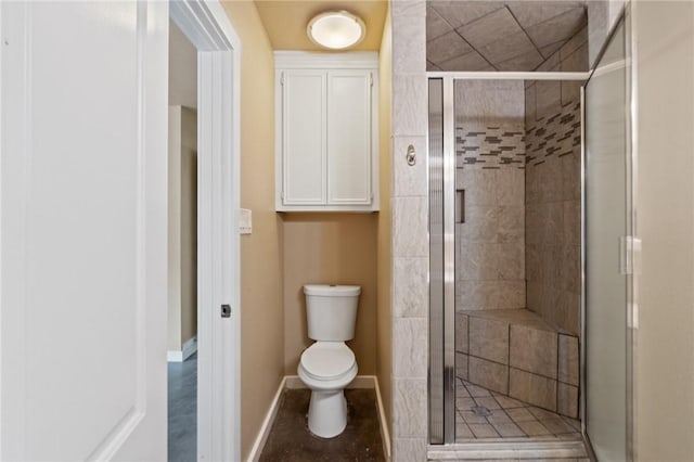 bathroom featuring baseboards, a shower stall, and toilet