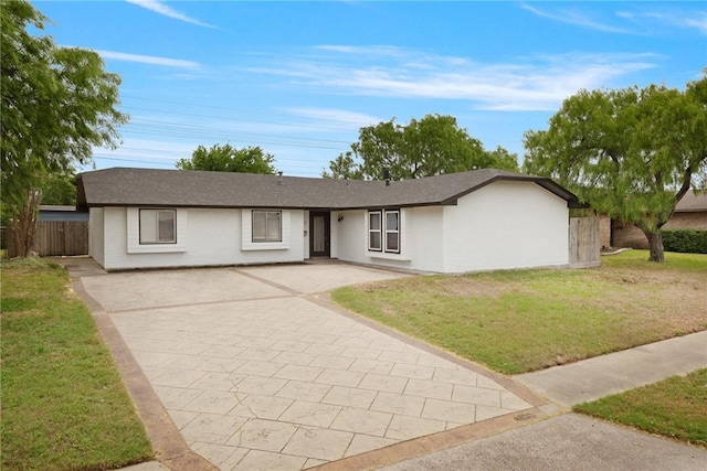 ranch-style home with driveway, fence, roof with shingles, and a front yard