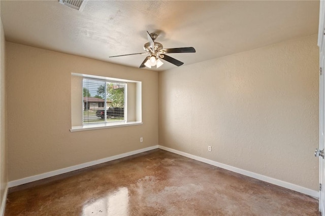 spare room featuring concrete floors, visible vents, a ceiling fan, and baseboards