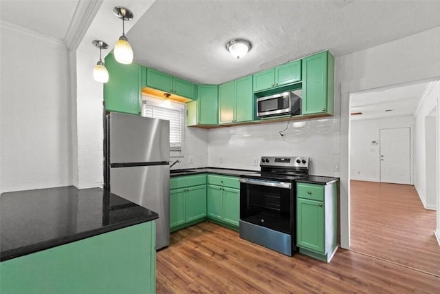 2853 Lawnview St, Corpus Christi, TX 78404 - kitchen featuring stainless steel appliances, crown molding, dark wood finished floors, green cabinetry, and hanging light fixtures