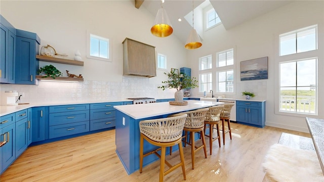 kitchen with dishwasher, premium range hood, a breakfast bar, and blue cabinetry