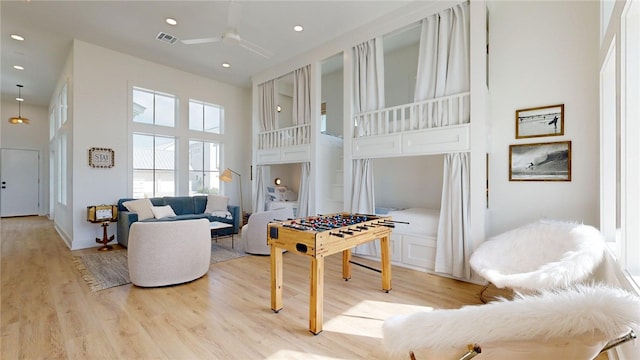 living area with recessed lighting, light wood-style flooring, a high ceiling, and ceiling fan
