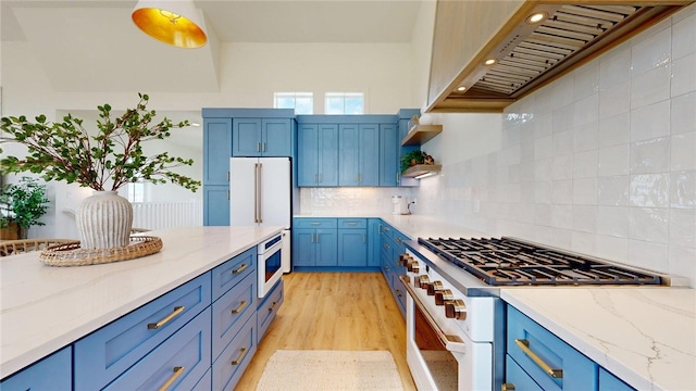 kitchen with custom exhaust hood, white appliances, light wood-style flooring, blue cabinetry, and backsplash