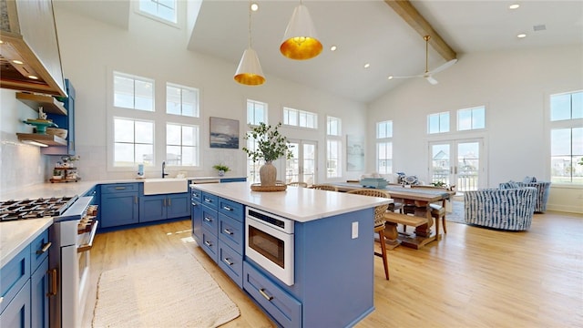 kitchen featuring light wood-style floors, beamed ceiling, blue cabinetry, a sink, and high end white range oven