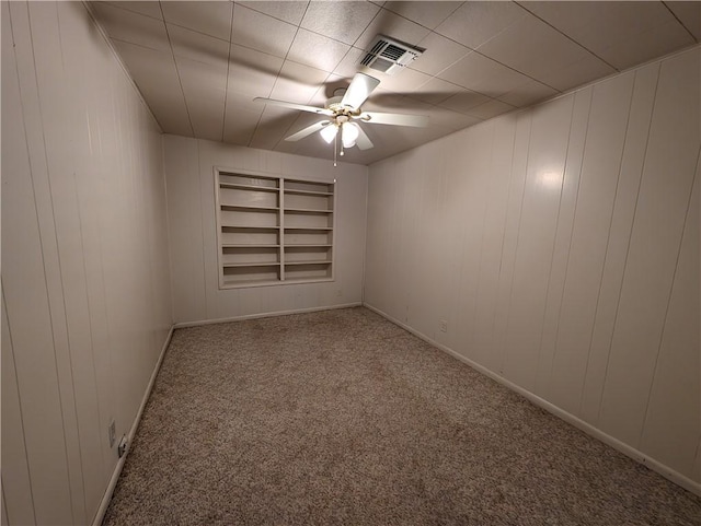 carpeted empty room with built in shelves and ceiling fan