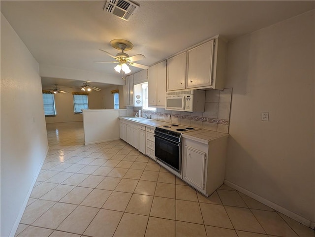 kitchen with tasteful backsplash, white cabinetry, and electric range oven