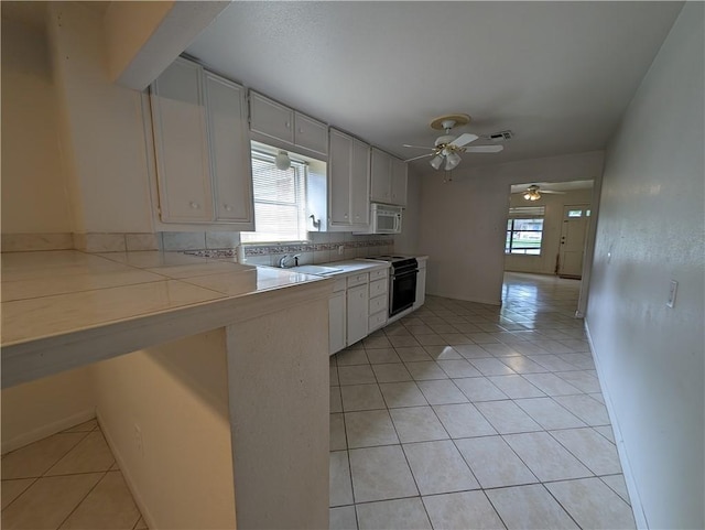 kitchen featuring white cabinets, decorative backsplash, black electric range oven, and light tile patterned floors