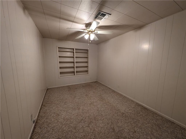 carpeted empty room with built in shelves and ceiling fan