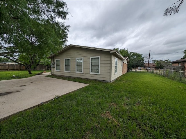 view of side of home with a patio and a lawn