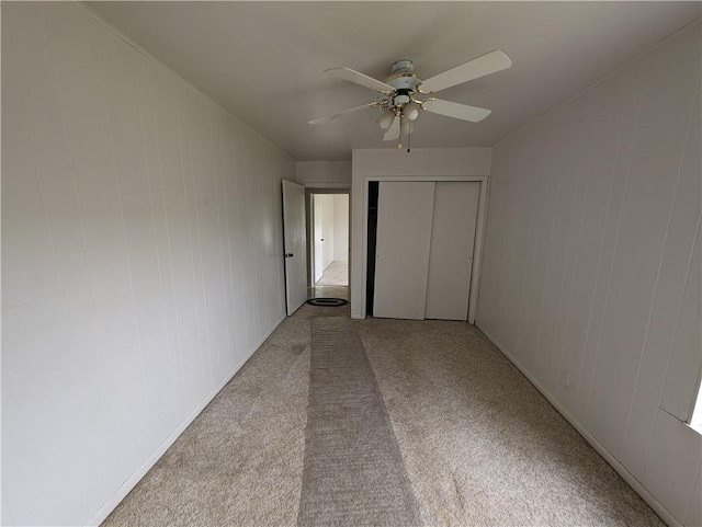 unfurnished bedroom with light carpet, a closet, and ceiling fan