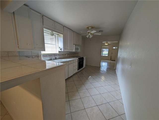 kitchen with white cabinetry, tile counters, electric range, decorative backsplash, and light tile patterned floors