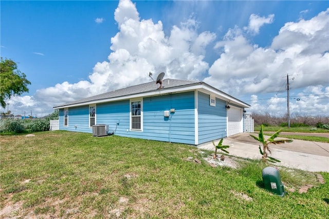 rear view of house featuring a garage, central AC, and a lawn