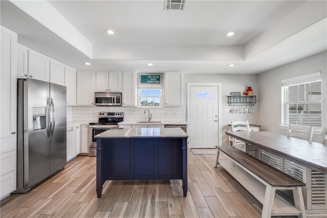 kitchen with appliances with stainless steel finishes, sink, white cabinets, and a tray ceiling