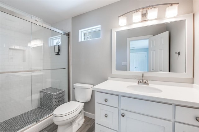 bathroom with vanity, hardwood / wood-style floors, a shower with shower door, and toilet