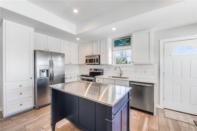 kitchen with sink, white cabinetry, a center island, appliances with stainless steel finishes, and backsplash