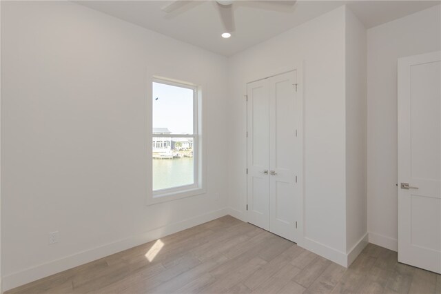 unfurnished bedroom featuring ceiling fan, a closet, and light wood-type flooring