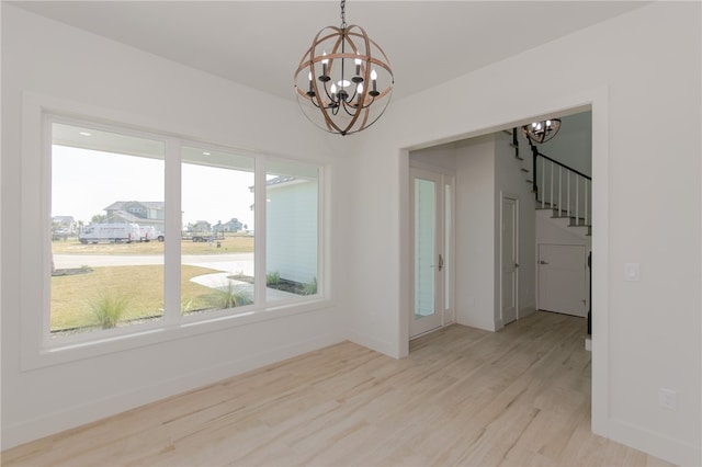 empty room with light hardwood / wood-style floors and an inviting chandelier