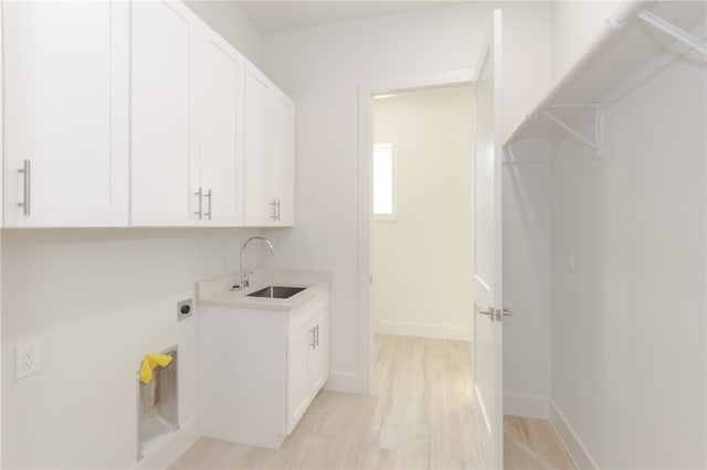 laundry area featuring cabinets, hookup for an electric dryer, sink, and light wood-type flooring