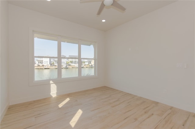 unfurnished room with light hardwood / wood-style floors, ceiling fan, and a water view