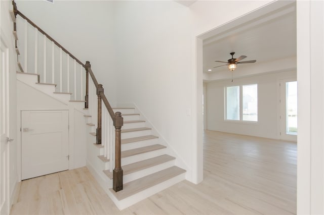 staircase with hardwood / wood-style floors and ceiling fan