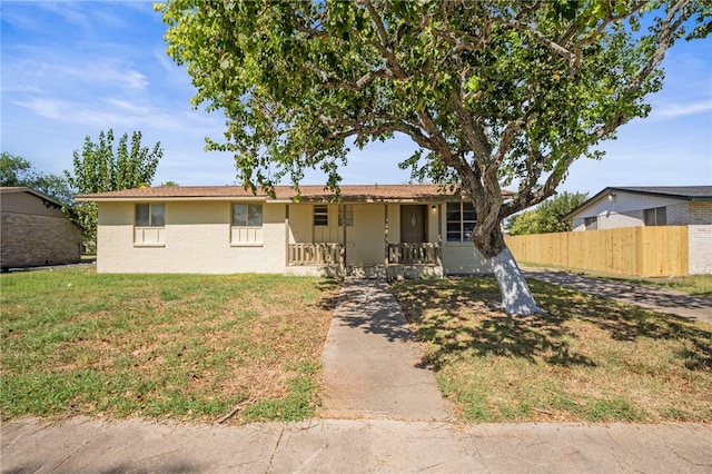 ranch-style home featuring covered porch and a front lawn