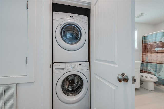 clothes washing area with laundry area, stacked washer and dryer, and visible vents