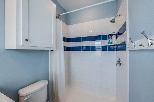 full bathroom with a tile shower and toilet