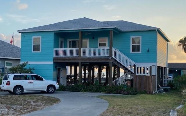 1811 Bay Shore Dr, Rockport, TX 78382 - raised beach house featuring curved driveway, covered porch, a front lawn, and stairway
