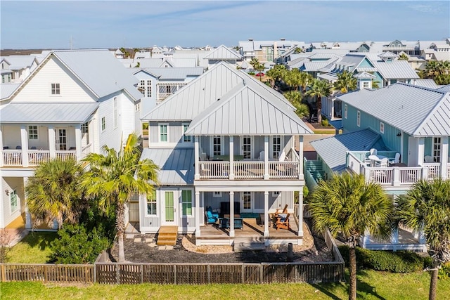 rear view of house with a balcony, a residential view, metal roof, fence private yard, and a standing seam roof