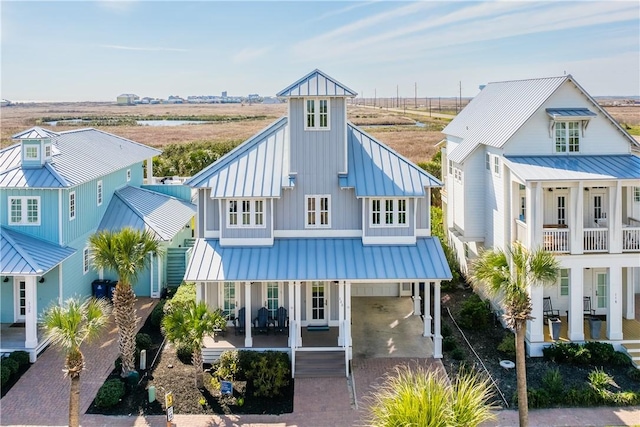 view of front of house with decorative driveway, a standing seam roof, metal roof, and a carport