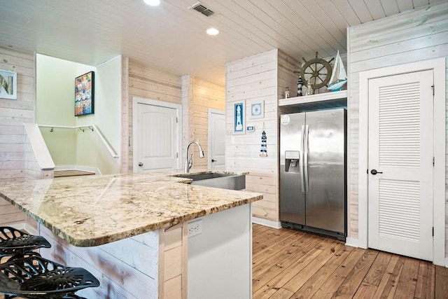 4903 State Highway 361 Unit 8, Port Aransas, TX 78373 - kitchen featuring stainless steel refrigerator with ice dispenser, wooden walls, light wood finished floors, recessed lighting, and a kitchen bar