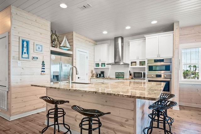 4903 State Highway 361 Unit 8, Port Aransas, TX 78373 - kitchen with wall chimney range hood, appliances with stainless steel finishes, light wood finished floors, a breakfast bar, and wood walls