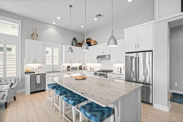 125 Reserve Ln, Rockport, TX 78382 - kitchen with high end appliances, under cabinet range hood, a high ceiling, a center island, and white cabinets