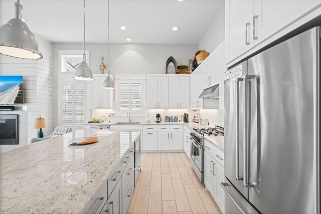 125 Reserve Ln, Rockport, TX 78382 - kitchen featuring high end appliances, under cabinet range hood, tasteful backsplash, light stone counters, and white cabinetry